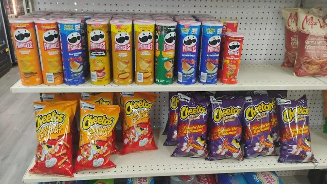 Pringles cans and Cheetos bags on the snack shelf at Northmount Convenience Store